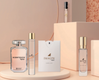 A clear glass perfume bottle with a silver cap, containing a light pink liquid. The label reads SCENTOUCH by Aptar, featuring a small iD Scent Technology logo and highlighting Reusable Paper Fragrance Sampling.