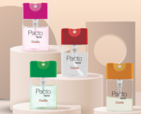 Four Purette Lotion bottles with flat mini packaging , each with a colorful cap : pink, red, green, and orange are displayed on beige circular platforms. The label reads 'Pacto by Aptar,' highlighting the compact format.