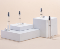 Four STILOs by Aptar are arranged in a staggered diagonal layout on white squared. Each vial features a slim, transparent body with a silver spray pump and cap, showcasing Aptar’s elegant and refillable fragrance mini packaging.