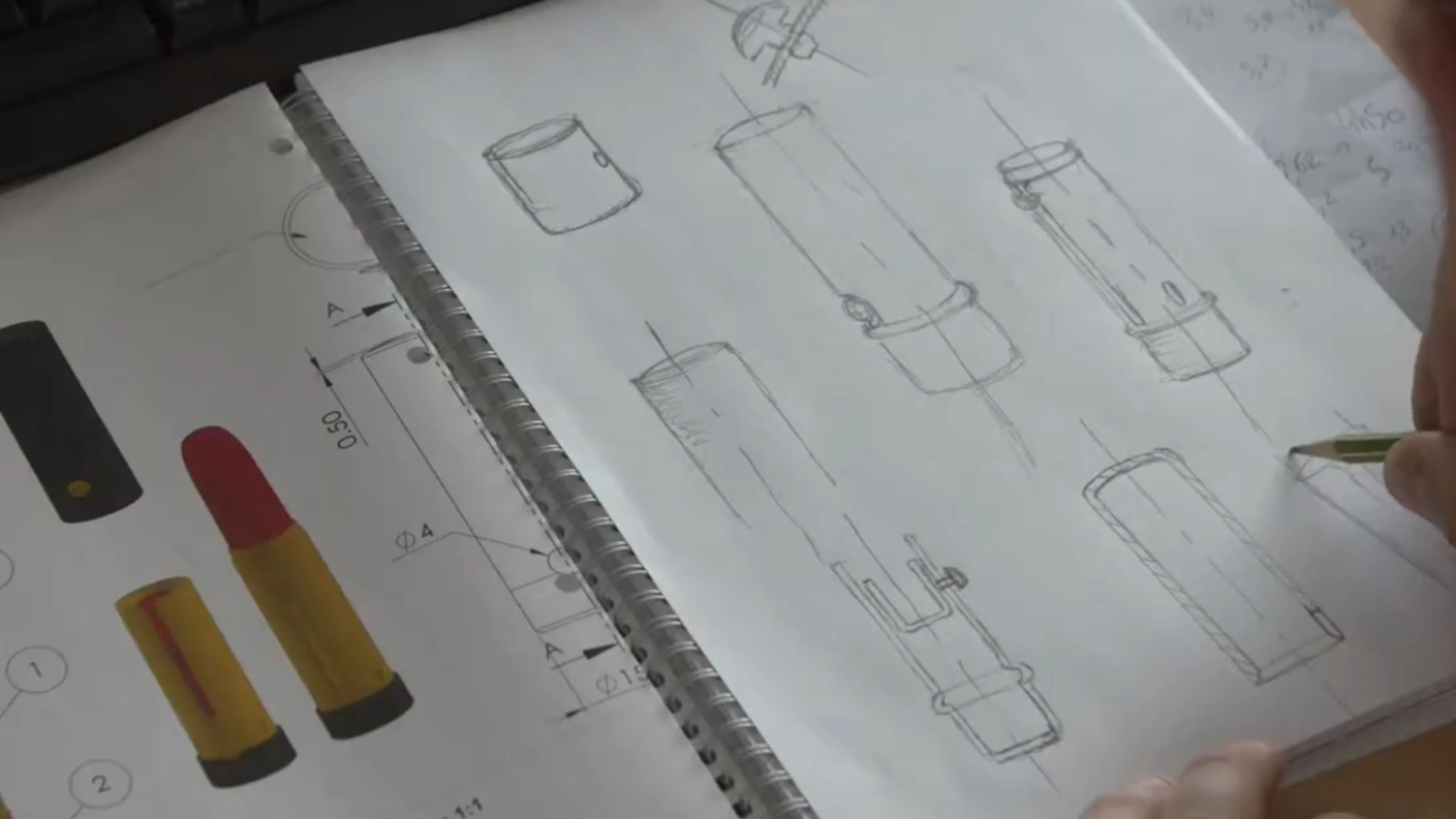 A person sketches technical drawings of cylindrical object, depicting a sketch of a lipstick case in a notebook, referencing a printed page with colored diagrams and measurements from a custom cosmetic packaging manufacturer.