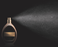 A refillable fragrance purse spray labeled "Precious" releases a fine mist into a dark background, with sparkling particles visible in the spray. The product, named Precious Sensea, features a sensorial prestige fragrance pump designed for a luxurious and refined application.