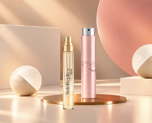 Mini fragrance packaging formats, including spray vials and travel-size fragrance containers, are arranged on a tabletop with soft lighting and geometric display elements.