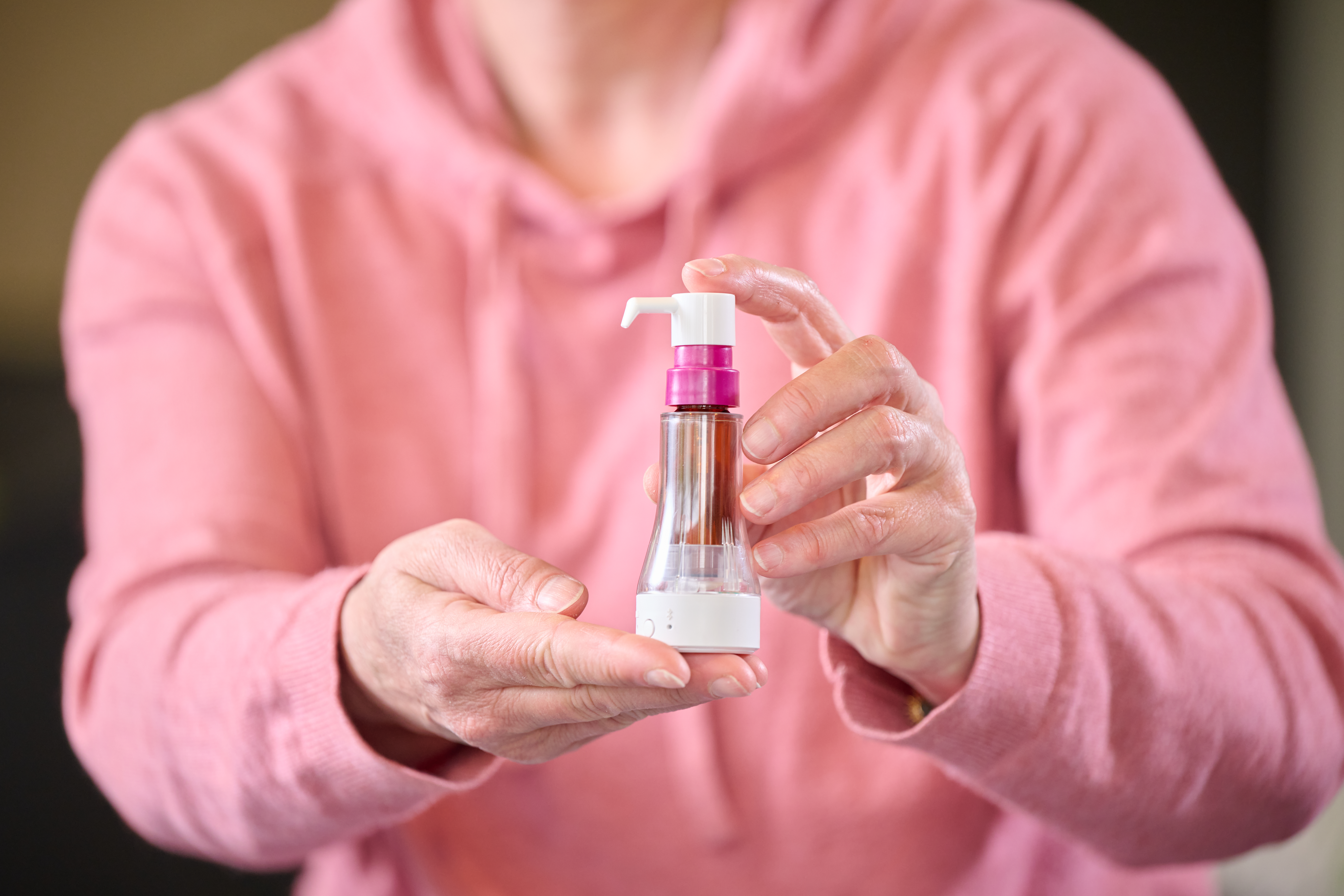 Person holding a connected drug delivery device designed to support accurate treatment administration.