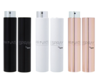 Three pairs of cylindrical refillable fragrance purse spray bottles black, white, and rose gold stand upright side by side. Each bottle is sleek and modern with metallic accents and labeled PRIVATE SPRAY by Aptar.
