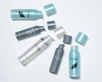 Five  of Aptar Beautay's best-selling airless packaging Mezzo in various sizes are arranged on a light surface. The metallic, iridescent bottles shimmer in shades of blue, silver, and grey, with some lids detached and placed nearby.