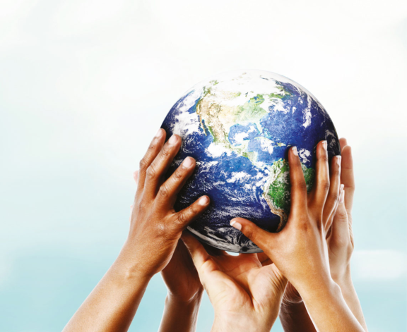 Globe being held up by group of human hands symbolizing Aptar team leadership in sustainability for the planet.