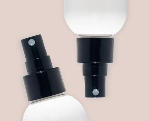 Close-up of two black Euromist 2-way spray pump bottle and white bottles, set against a light beige background.