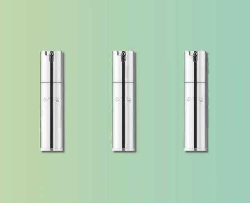 Three sleek, silver cylindrical bottles labeled Auriga City are evenly spaced against a soft green-to-blue gradient background. Each features luxury airless packaging with a minimalist design, subtle text, and a spray nozzle on top.