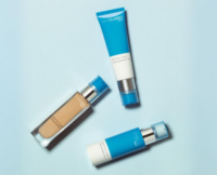 Three skincare product bottles with blue and white packaging, each featuring a reliable cosmetic pump labeled Evoclassic, are arranged diagonally on a light blue background. One bottle contains foundation, while the other two appear to be creams or lotions.