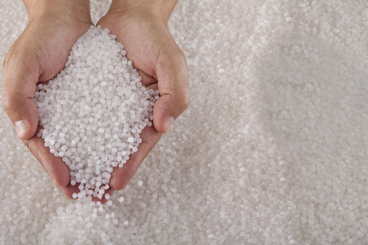 Two human hands holding small beads of recycled circular feedstock materials for APF futurity systems.