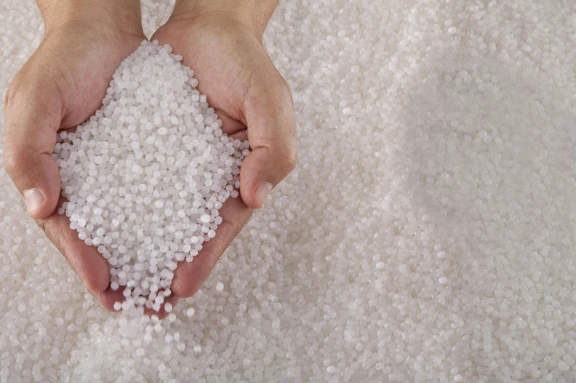 Two human hands holding small beads of recycled circular feedstock materials for APF futurity systems.