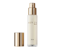 A single, elegant bottle stands upright against a clean, white background. The packaging features Aptar Beauty’s Astrea airless glass dispenser, highlighted by a luxurious gold actuator and matching cap placed beside it.