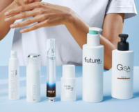A persons hands hover above a row of six skincare or cosmetic bottles labeled Irresistible,Mezzo,Star Drop , GSA, Future and Serumony on a light blue surface.