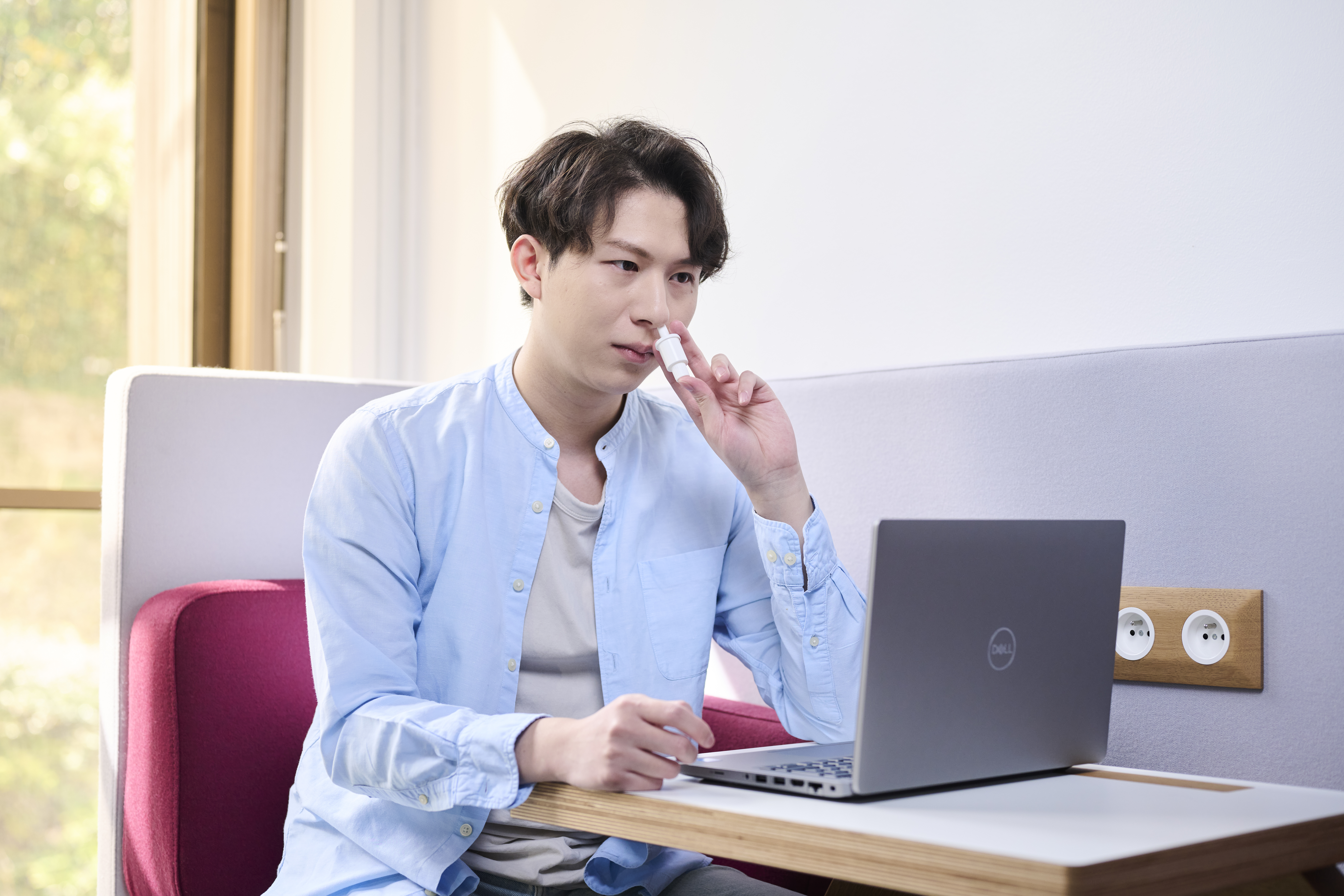A man with a computer administering a single precise powder dose from an Aptar Unidose Powder Nasal Drug delivery system