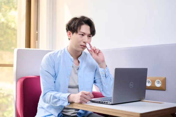 A man with a computer administering a single precise powder dose from an Aptar Unidose Powder Nasal Drug delivery system