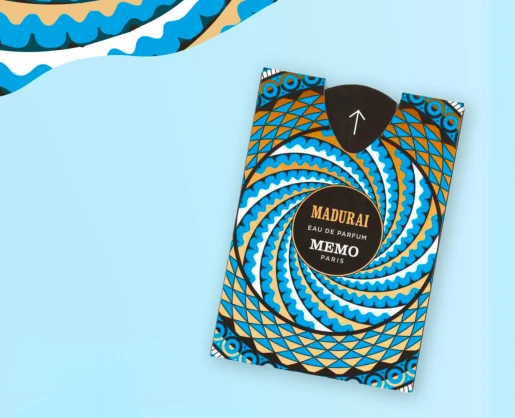 A perfume box labeled MADURAI MEMO PARIS with a bold, geometric blue, white, black, and gold circular pattern on a light blue background. Ultra-flat fragrance sampling packaging is partially visible in the top left corner.