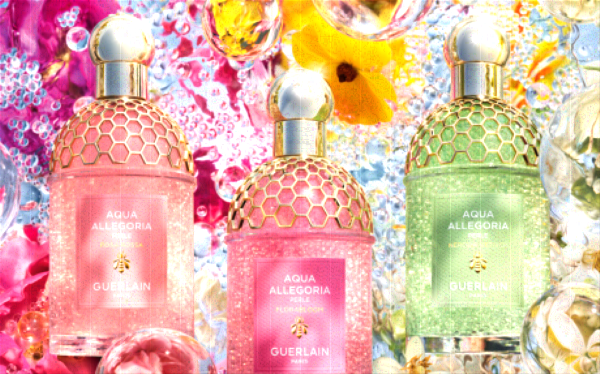 Three Peach Pink and Green Fragrance Bottles of Guerlain Aqua Allegoria Perle with Golden Caps and Details on Flower and Droplets Background