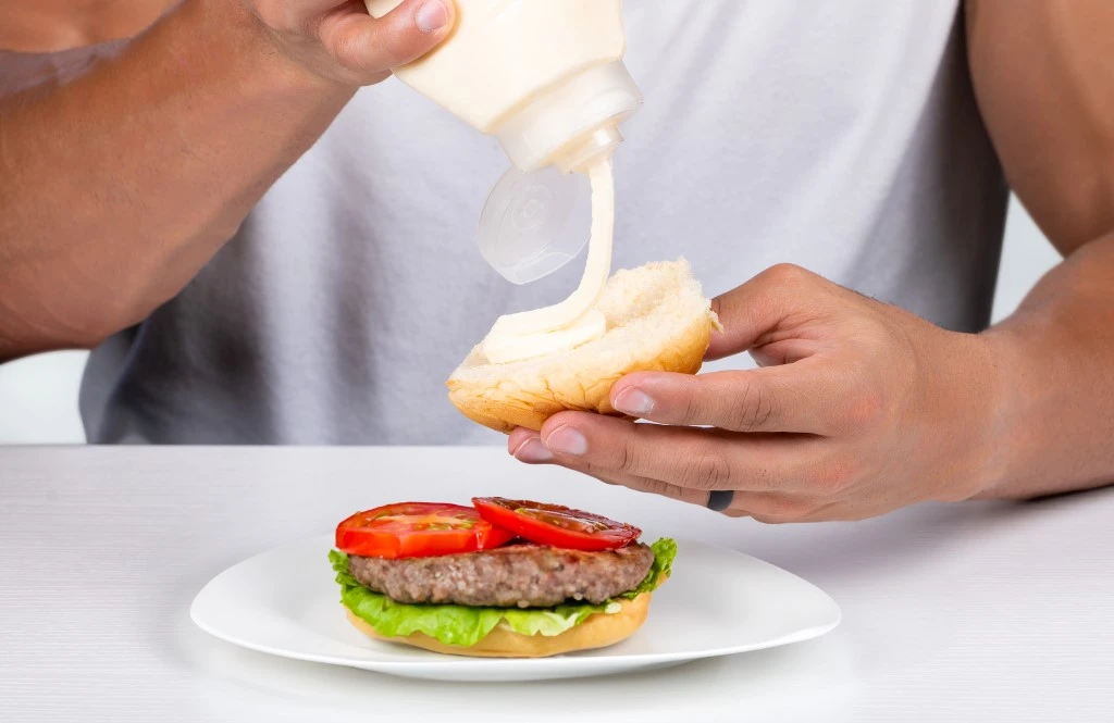 Squeezing mayo onto burger