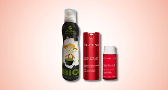 A black and white aerosol packaging for olive oil next to a red Clarins skincare packaging with reload on pink gradient background