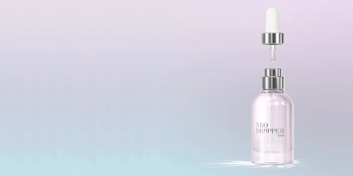 A clear glass bottle labeled NEO DROPPER with elegant dropper packaging and a silver cap, set against a soft pastel gradient background. The dropper floats above the bottle, with a single drop about to fall.