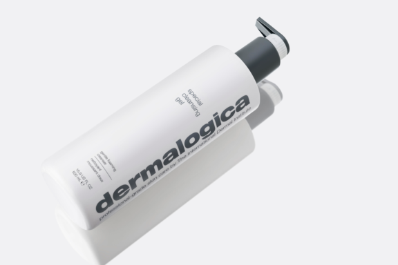 A white bottle of Dermalogica Special Cleansing Gel featuring Future,  a fully recyclable dispensing pump lies on its side against a light background. The label features bold gray text, and a subtle shadow is cast beside the bottle.