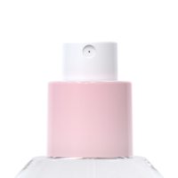 Close-up of a perfume bottle featuring the Color Screw refillable plastic fragrance pump in light pink and white, mounted on a clear glass base and set against a white background
