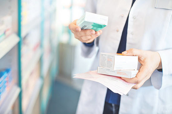 Pharmacist’s hands taking medicines from shelf