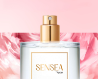 A clear perfume bottle labeled SENSEA by Aptar with a gold high quality prestige fragrance pump, set against a pink and white floral background.
