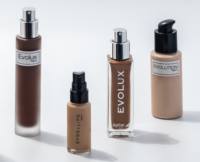 Four bottles of cosmetics in varying sizes and shapes, labeled Evolux, Eyes & Lips, a micro-dosage cosmetic pump, and Evolution, are arranged on a white surface with soft shadows. Each features a variety of various liquid shades.