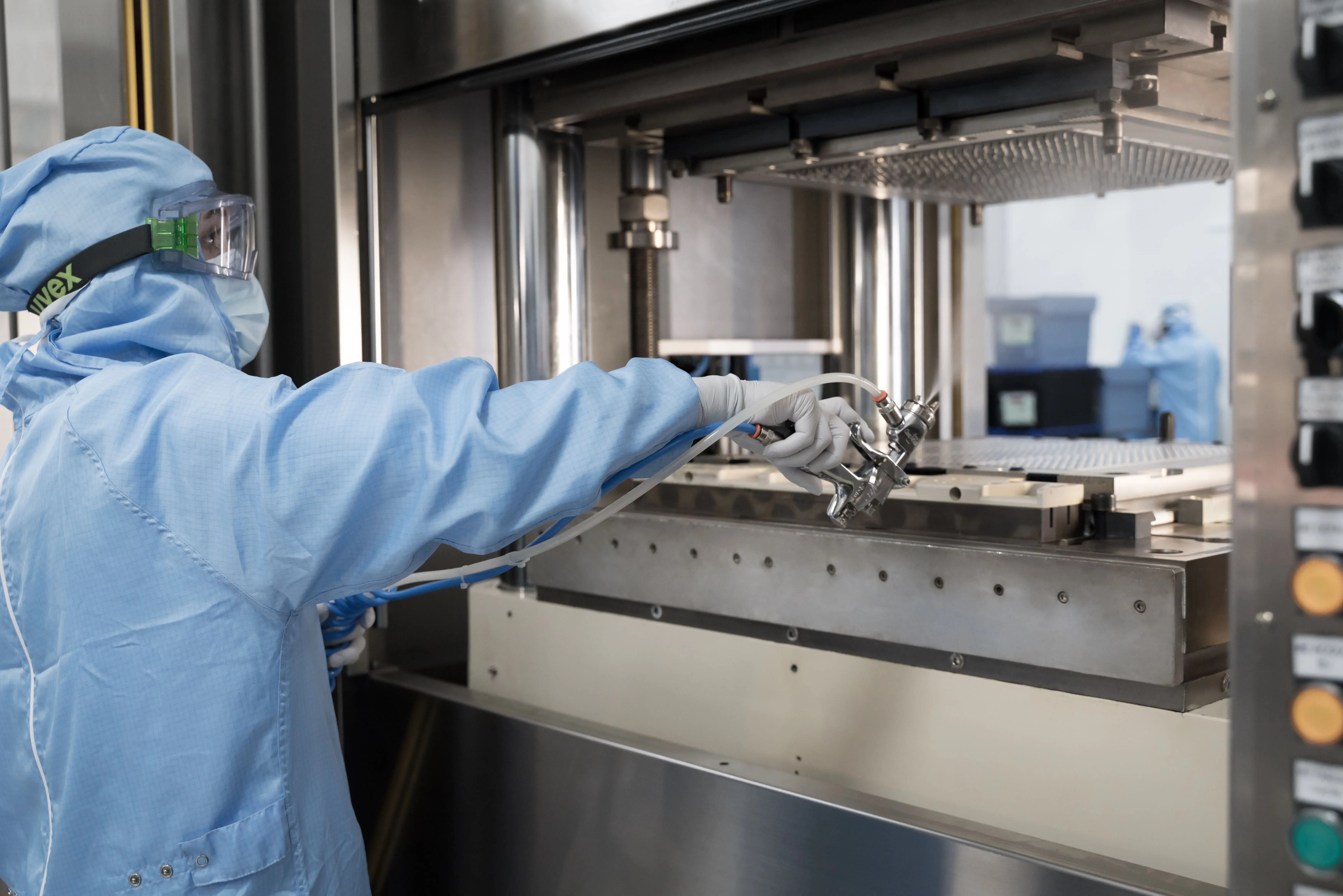 Operator in cleanroom gown using equipment in sterile manufacturing environment under controlled conditions