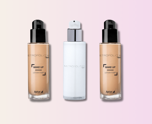 Three versatile cosmetic pumps labeled Metropolitan are displayed side by side against a pink and beige gradient background. The outer bottles contain beige makeup, while the center bottle is white. All have black or white caps.