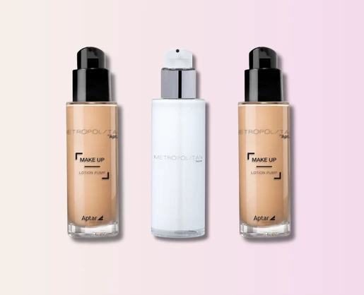 Three versatile cosmetic pumps labeled Metropolitan are displayed side by side against a pink and beige gradient background. The outer bottles contain beige makeup, while the center bottle is white. All have black or white caps.