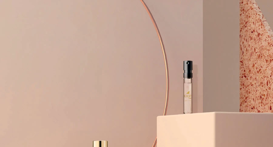 A minimalist scene with a small perfume bottle on a square pedestal and another spray bottle in the background, evoking elegant fragrance sampling labeled Easy Spray, set against a soft beige wall with a copper arc and textured accent.