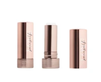 Three rose gold non guided mini lipstick packaging tubes are shown, two with their caps on and one in the center with the cap off to display the balm inside. The tubes feature elegant script writing on the side.