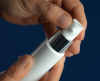 a picture of a white airless pump bottle with a silver collar held in two hands, indicating the actuator is twisting on a dark blue background.