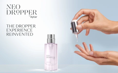 A hand holds a dropper above an open palm with a clear liquid droplet about to fall, beside a transparent bottle labeled NEO DROPPER by Aptar, showcasing innovative dropper packaging and the text THE DROPPER EXPERIENCE REINVENTED on a light background.