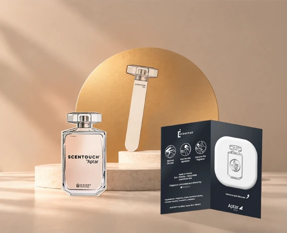 A paper-based fragrance sampling card, scented applicator, and fragrance bottle are displayed together on a softly lit tabletop, showcasing fragrance discovery and sampling solutions.