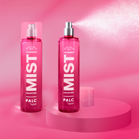 Two pink bottles labeled MIST stand on a pink surface, showcasing elegant fragrance mist packaging; one capped, the other releasing a fine spray. The monochromatic pink background and pedestal complete the stylish, modern look.
