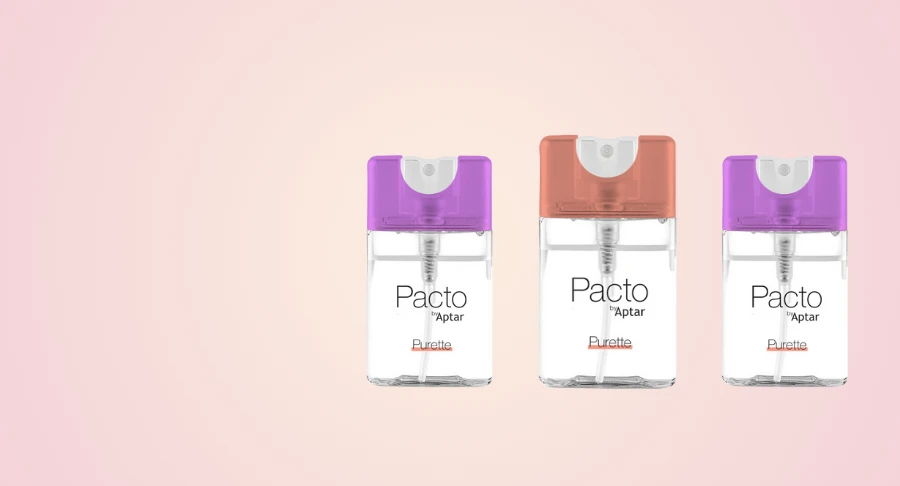 Three Purette Fine Mist flat mini packaging spray bottles labeled 'Pacto by Aptar' with purple, orange, and lilac caps, displayed side by side on a pink gradient background.