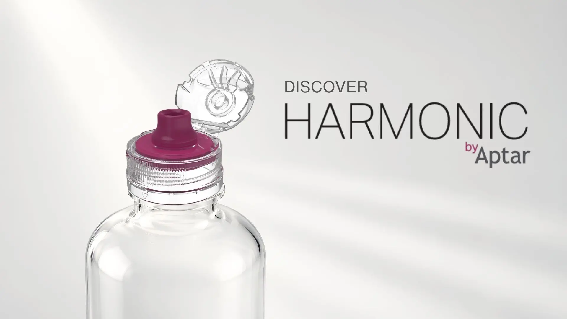 Transparent flip-top beverage closure with a dispensing spout shown open on a clear bottle, alongside the text “Discover HARMONIC by Aptar” on a light gray background.