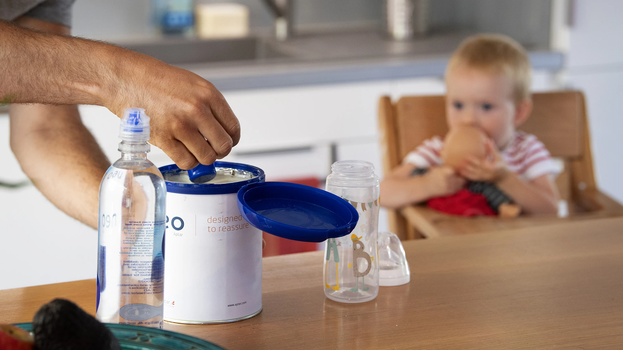 a parent scooping infant formula into a baby bottle