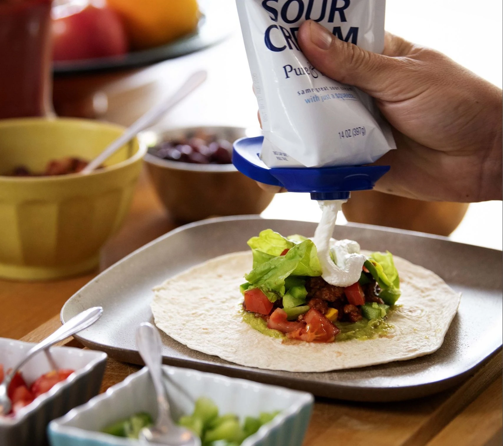 Dispensing sour cream dairy product from stand-up pouch onto taco