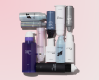 A variety of skincare or color cosmetic airless packaging bottles in different sizes and pastel colors are arranged neatly on a pale pink background. The containers, featuring bottom fill airless packaging, are labeled with names like macro oval, mini oval, and mezzo.
