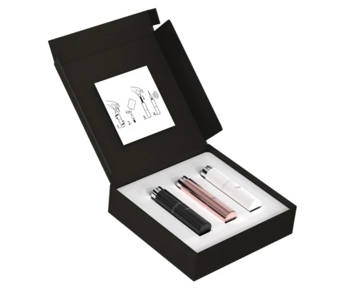 An open black gift box holds three sleek refillable fragrance purse sprays in black, rose gold, and white, with an instruction card showing how to use the atomizers.