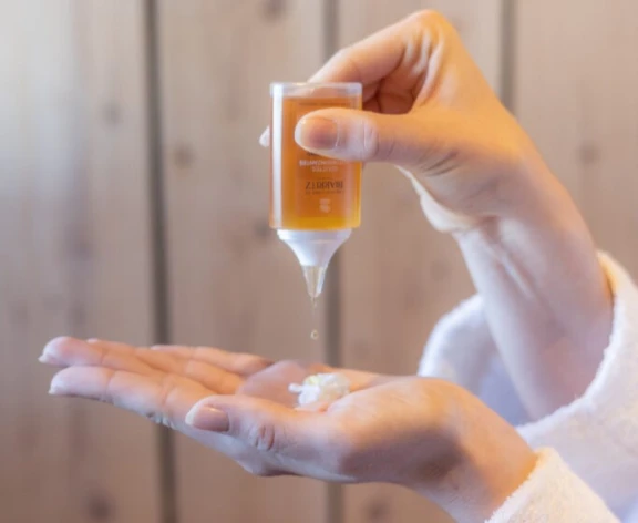 a person in a robe holding Aptar Beauty's Star Drop dropper for color cosmetics, personal care and skincare