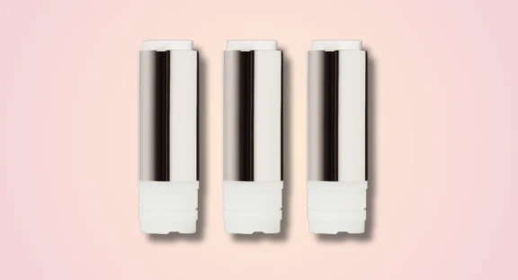Three identical Non-Guided Lipstick Mechanism for Rigid Formulas with white and silver bodies are arranged vertically in a row, resembling the precise alignment, against a light pink background.