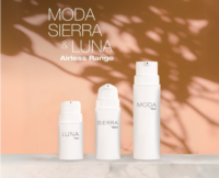 Three white high-performance airless pump bottles labeled LUNA, SIERRA, and MODA sit on a marble surface with a warm peach background and leafy shadows. Text above reads MODA SIERRA & LUNA Airless Range.