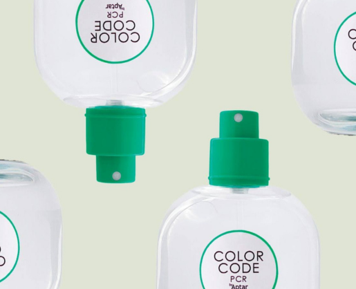 Four clear bottles, feature a Color Code PCR fragrance pump. Arranged on a light beige background, the bottles are displayed from different angles some upright and some upside down.