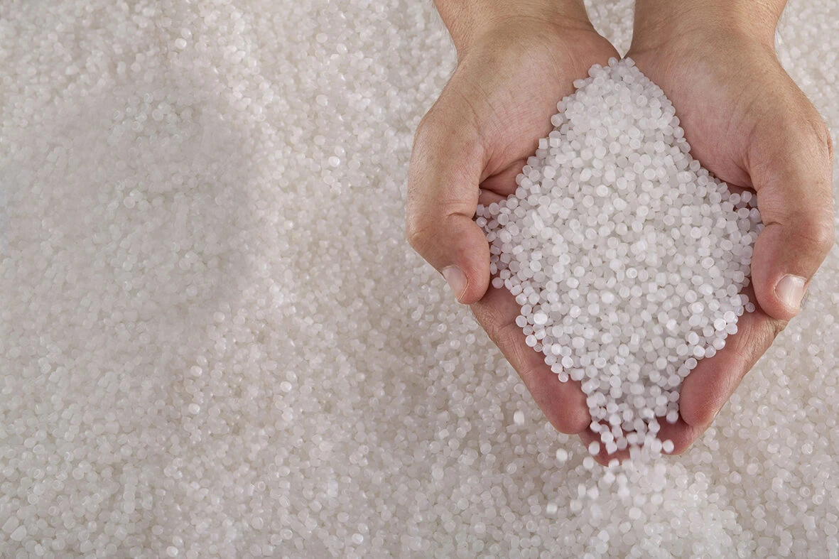 Two human hands holding small beads of recycled circular feedstock materials for APF futurity devices.