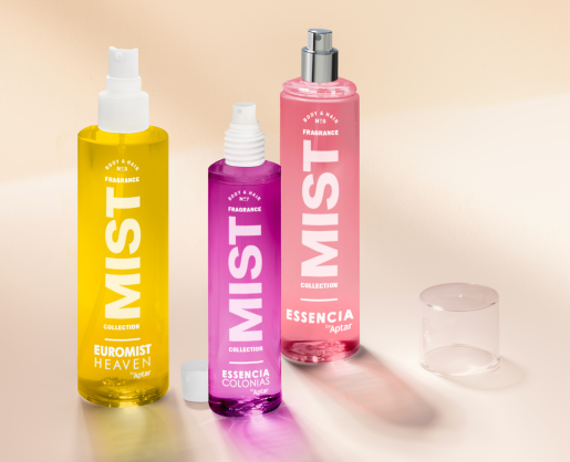 Three colorful fragrance mist bottles yellow, purple, and pink stand on a light surface, offering a discreet refillable fragrance experience. Each bottle features bold white text and a white or clear spray cap, with one cap placed nearby.